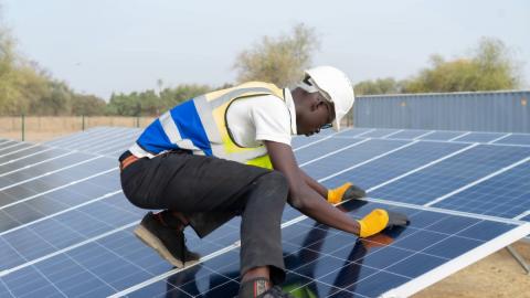 Un homme avec un casque et des gants en train de travailler sur un panneau solaire